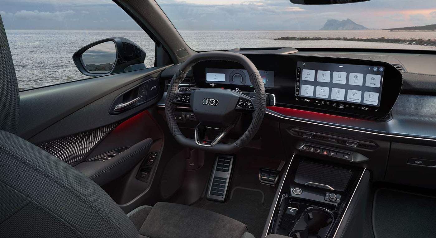 Modern car interior of Audi Q3 with sleek dashboard, digital displays, and a view of the ocean at sunset through the windshield, conveying a sense of luxury.